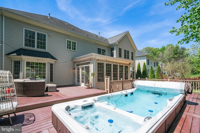 wooden deck with hot tub deck surround and a sunroom
