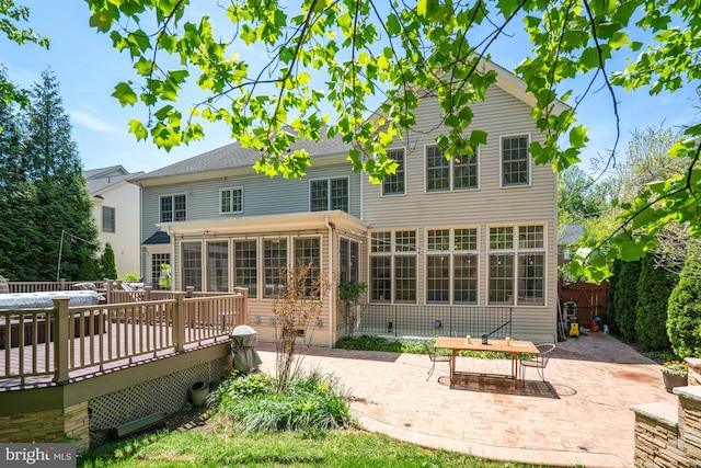 back of property featuring a deck, a sunroom, fence, a patio, and outdoor dining space