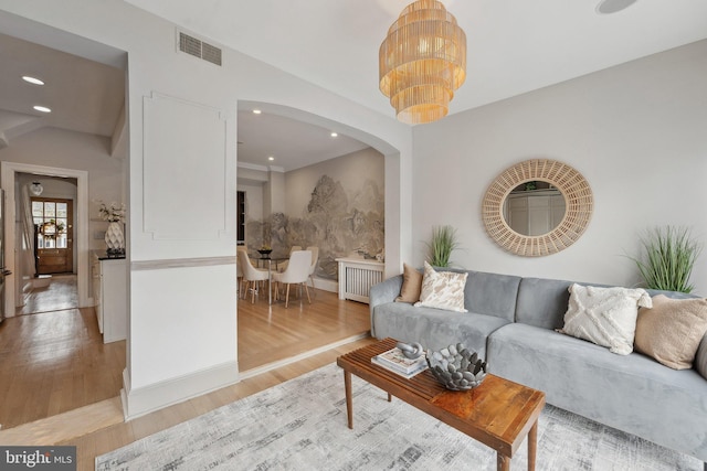 living room with light wood finished floors, recessed lighting, visible vents, and arched walkways