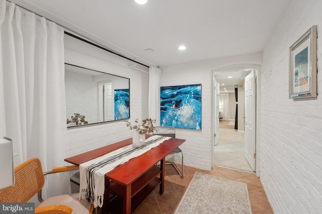 hallway with light tile patterned floors, brick wall, and recessed lighting