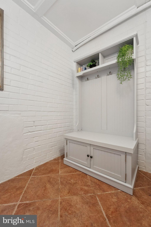 mudroom with tile patterned flooring and brick wall