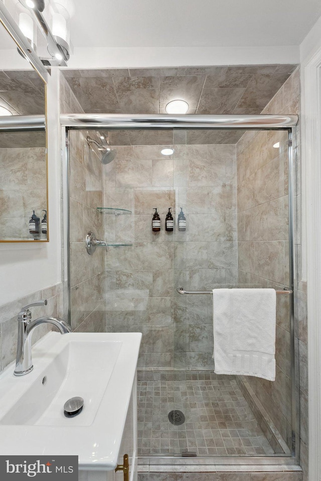 full bath with tile walls, a stall shower, and vanity