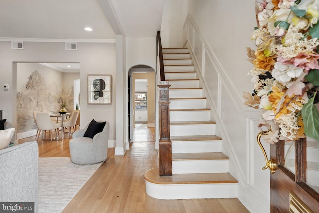 stairs with visible vents, arched walkways, wood finished floors, and recessed lighting