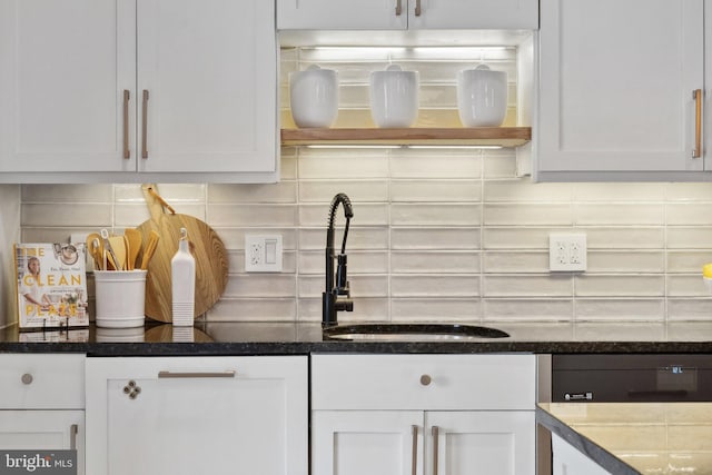 kitchen with a sink, white cabinets, and backsplash