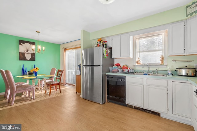 kitchen featuring a wealth of natural light, a sink, freestanding refrigerator, a chandelier, and black dishwasher