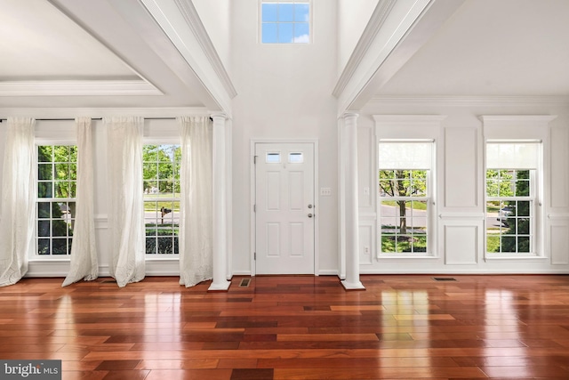 foyer with decorative columns, ornamental molding, visible vents, and hardwood / wood-style floors