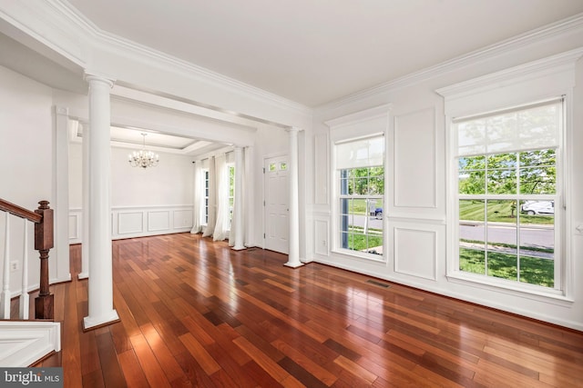 unfurnished living room featuring visible vents, a decorative wall, ornate columns, a chandelier, and hardwood / wood-style flooring