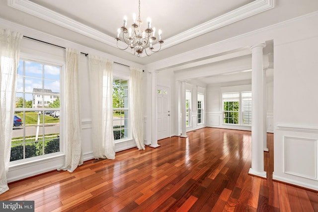interior space with an inviting chandelier, ornamental molding, decorative columns, and hardwood / wood-style floors
