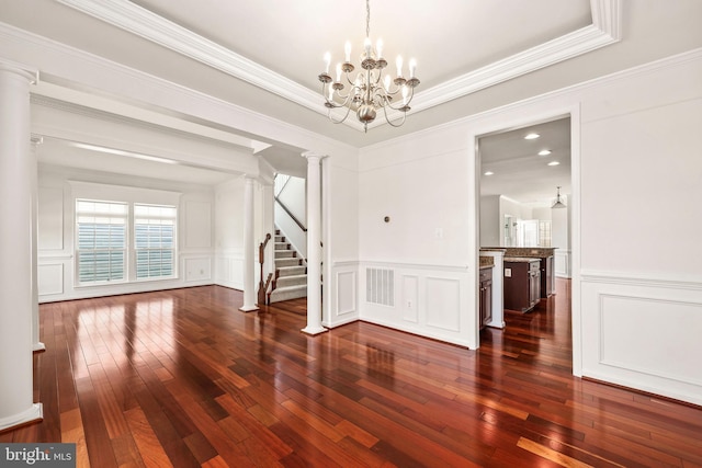 unfurnished dining area featuring hardwood / wood-style flooring, a decorative wall, stairs, and visible vents