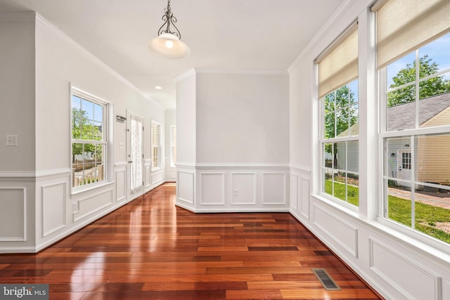 spare room featuring visible vents, ornamental molding, a wealth of natural light, and dark wood finished floors