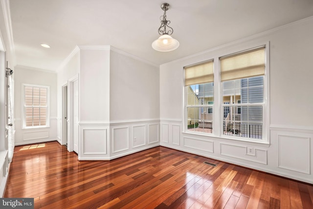 spare room featuring a healthy amount of sunlight, crown molding, wood-type flooring, and visible vents