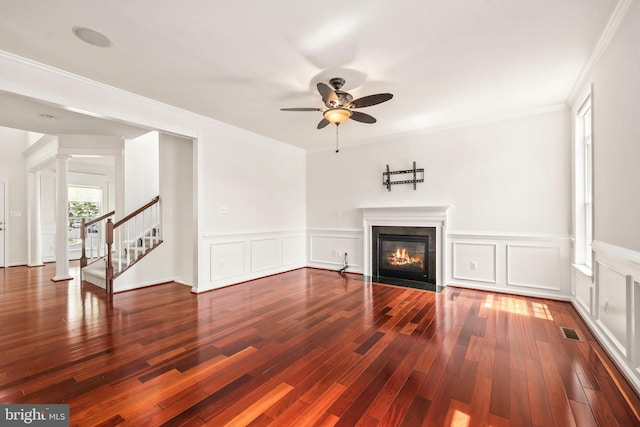 unfurnished living room featuring ceiling fan, a decorative wall, a fireplace with flush hearth, wood finished floors, and visible vents