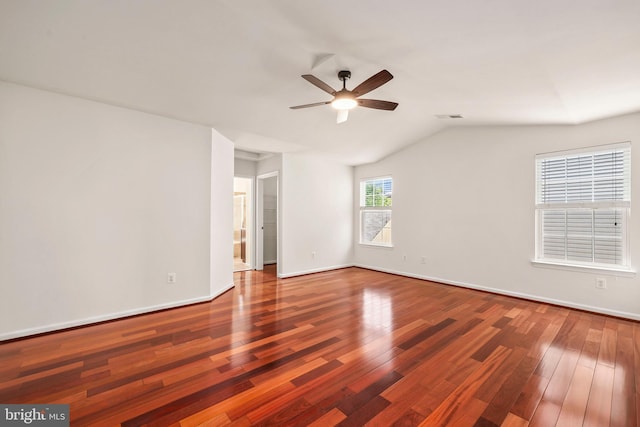 empty room featuring a ceiling fan, visible vents, vaulted ceiling, wood finished floors, and baseboards