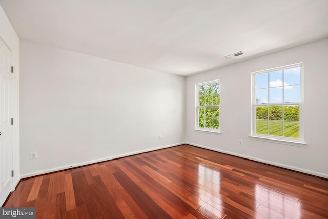 spare room with baseboards, wood finished floors, and visible vents