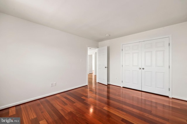 unfurnished bedroom featuring baseboards, a closet, and wood finished floors