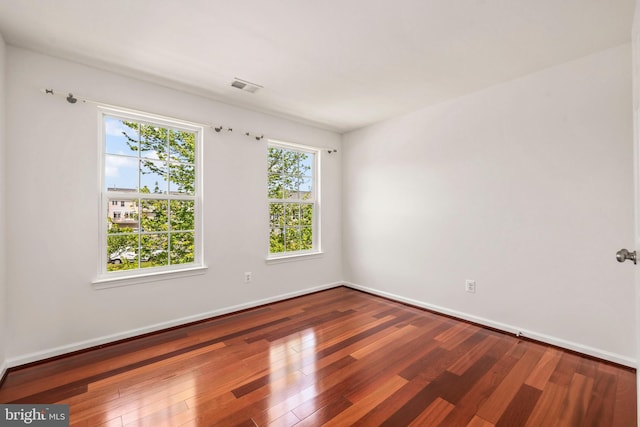 unfurnished room featuring baseboards, wood finished floors, and visible vents