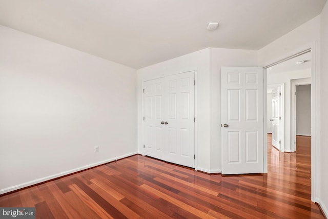 unfurnished bedroom with baseboards, a closet, and dark wood-style flooring