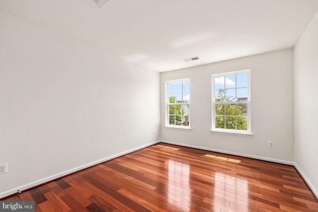 unfurnished room with wood-type flooring, baseboards, and visible vents