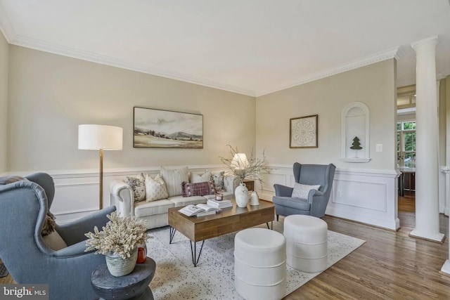 living room with crown molding, decorative columns, and wood finished floors