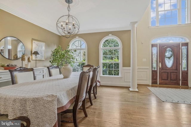 dining room featuring a notable chandelier, decorative columns, wainscoting, and wood finished floors