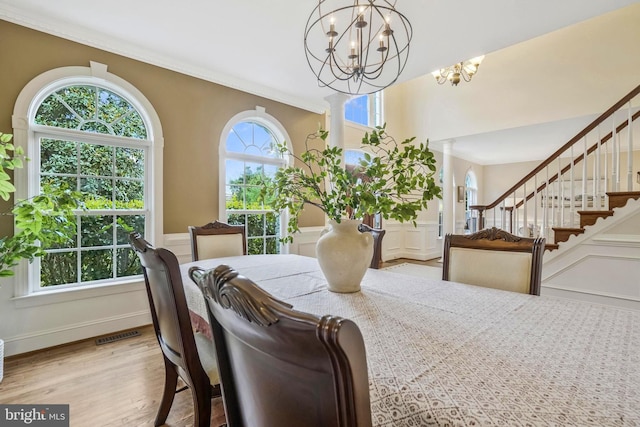 dining room featuring crown molding, wood finished floors, a chandelier, and a wainscoted wall