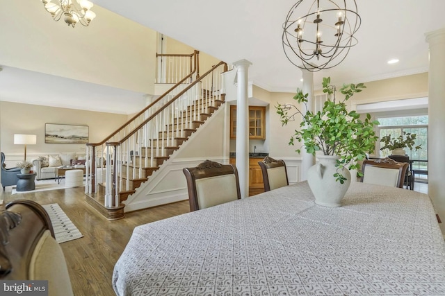 dining room with ornate columns, a chandelier, and wood finished floors