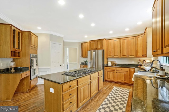 kitchen with a sink, light wood-style floors, a center island, stainless steel appliances, and ornamental molding