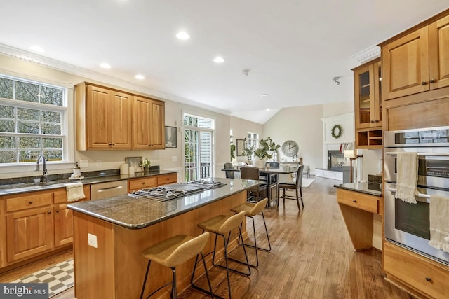 kitchen featuring appliances with stainless steel finishes, a breakfast bar, a sink, recessed lighting, and a kitchen island