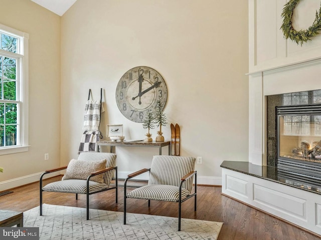 sitting room with baseboards, a high end fireplace, and dark wood-type flooring