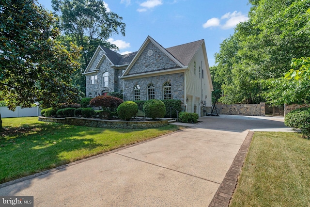 view of front facade featuring fence, driveway, stone siding, and a front lawn