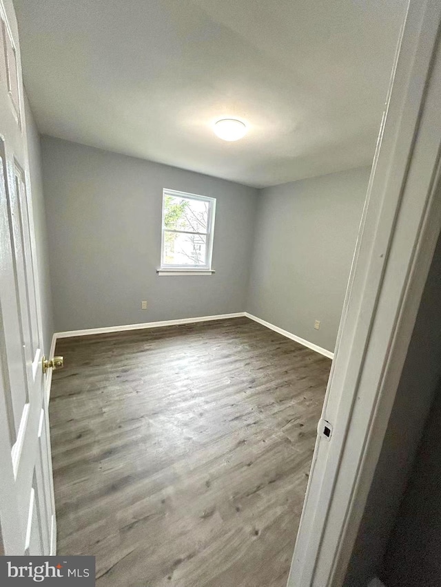 unfurnished room featuring baseboards and wood finished floors