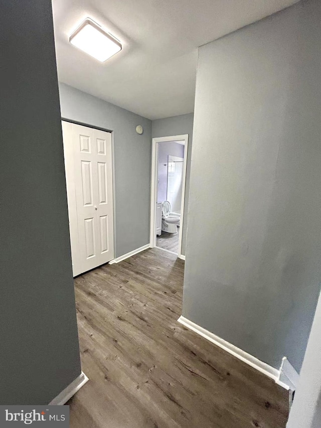 corridor featuring baseboards and wood finished floors