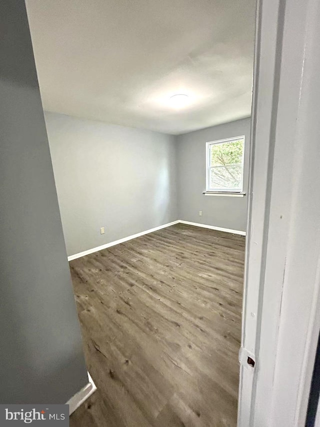 empty room with dark wood-style floors and baseboards