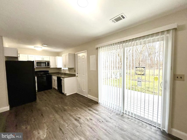 kitchen featuring a sink, dark wood-style floors, visible vents, white cabinets, and black appliances
