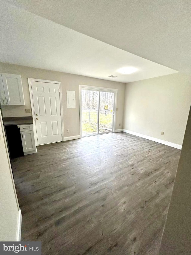 unfurnished living room featuring baseboards, dark wood-style floors, and visible vents