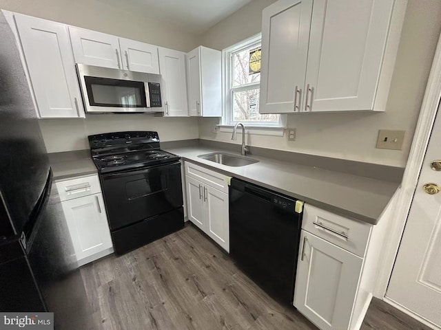 kitchen with light countertops, a sink, white cabinets, dark wood-style floors, and black appliances
