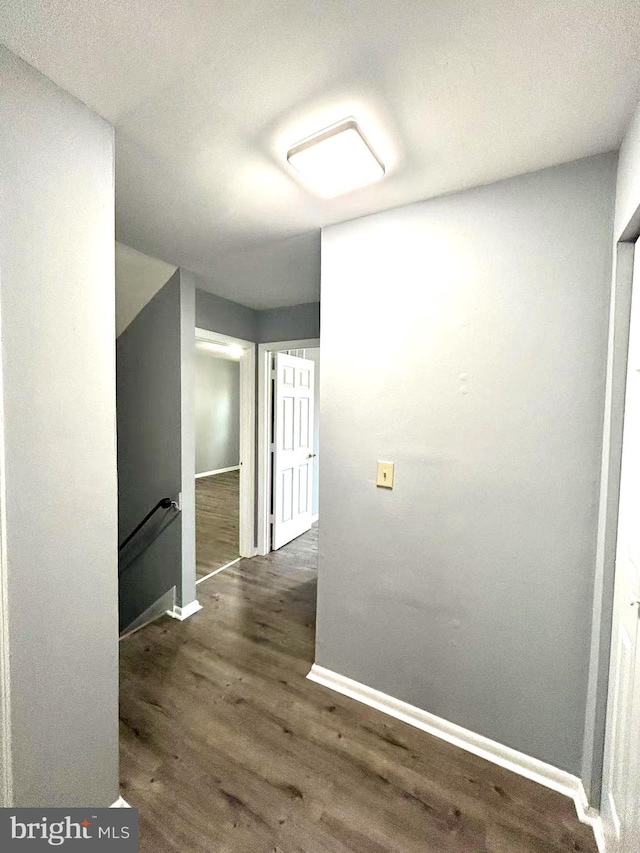 corridor featuring baseboards, an upstairs landing, and wood finished floors