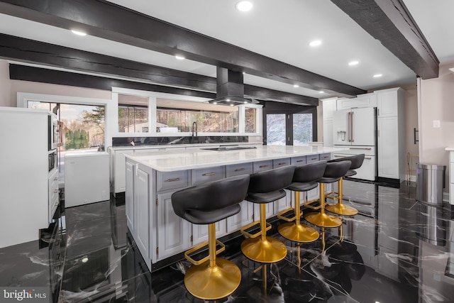 kitchen with island range hood, marble finish floor, high end fridge, and beam ceiling