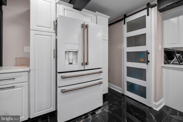 kitchen featuring white cabinets, baseboards, marble finish floor, a barn door, and white refrigerator with ice dispenser