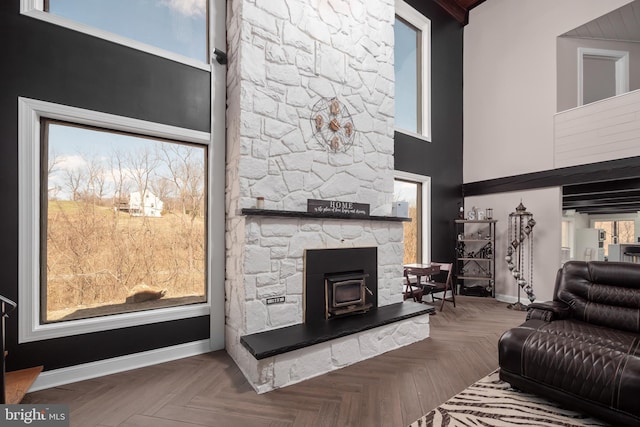 living room with baseboards, a towering ceiling, and a wood stove