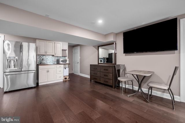 kitchen featuring dark wood-style flooring, white microwave, high end fridge, and tasteful backsplash
