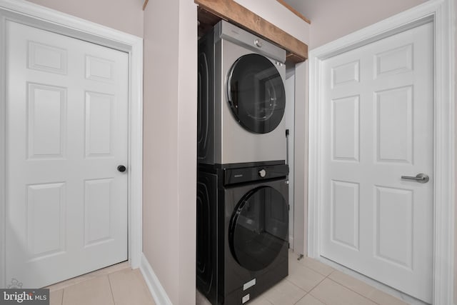 washroom featuring stacked washer / dryer, light tile patterned floors, and laundry area