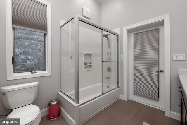 full bathroom with baseboards, bath / shower combo with glass door, toilet, and vanity