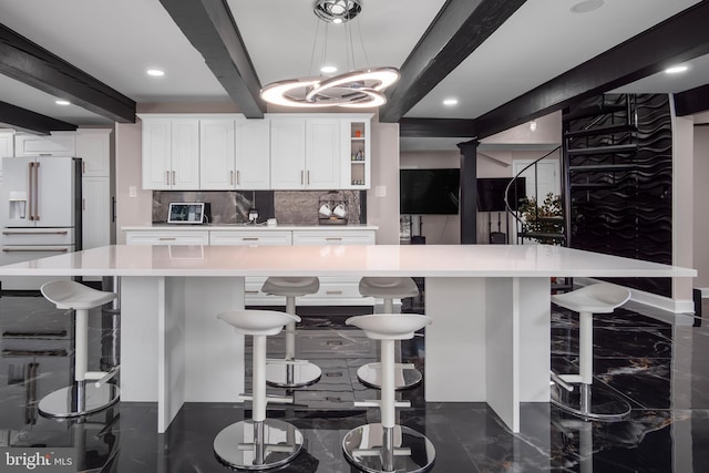 kitchen featuring light countertops, white cabinets, beamed ceiling, marble finish floor, and high end white refrigerator