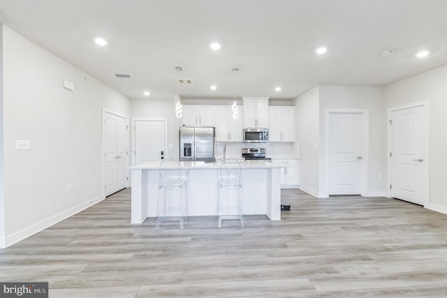 kitchen with light countertops, white cabinetry, appliances with stainless steel finishes, a kitchen island with sink, and visible vents