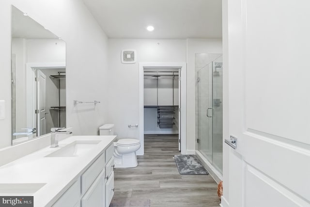 full bathroom with a sink, a stall shower, a walk in closet, and wood finished floors