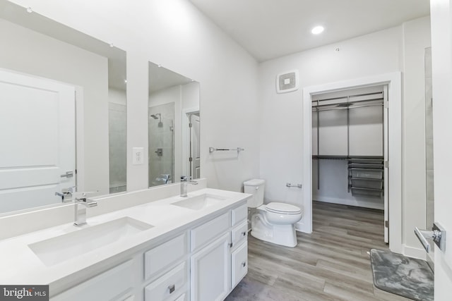 full bathroom with a stall shower, wood finished floors, toilet, and a sink