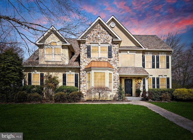 craftsman-style home with a yard, stone siding, and stucco siding