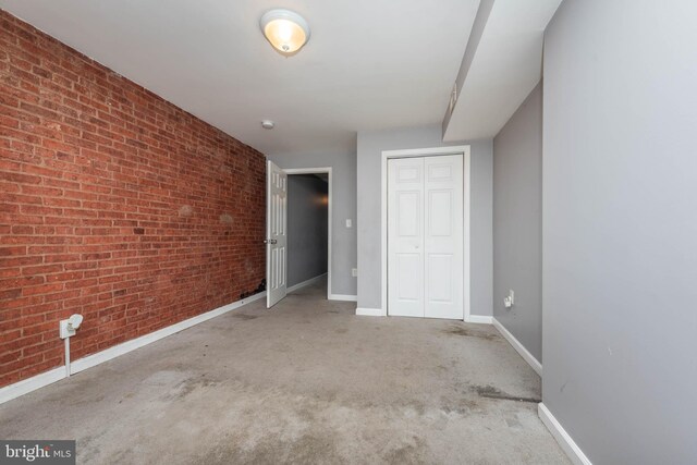 2110 E Hoffman St, Baltimore, MD 21213 - unfurnished bedroom with carpet floors, brick wall, baseboards, and a closet
