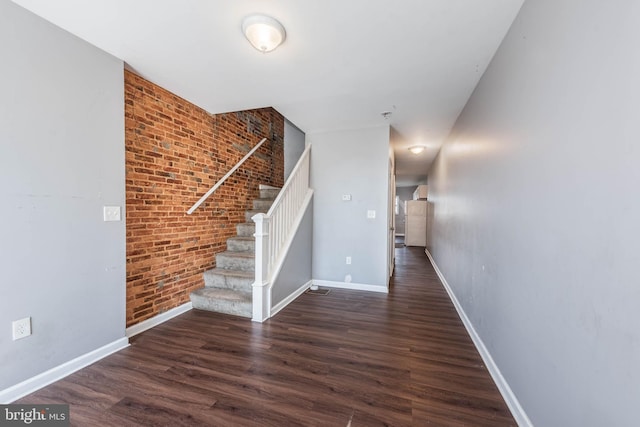 2110 E Hoffman St, Baltimore, MD 21213 - stairway with baseboards, wood finished floors, and brick wall